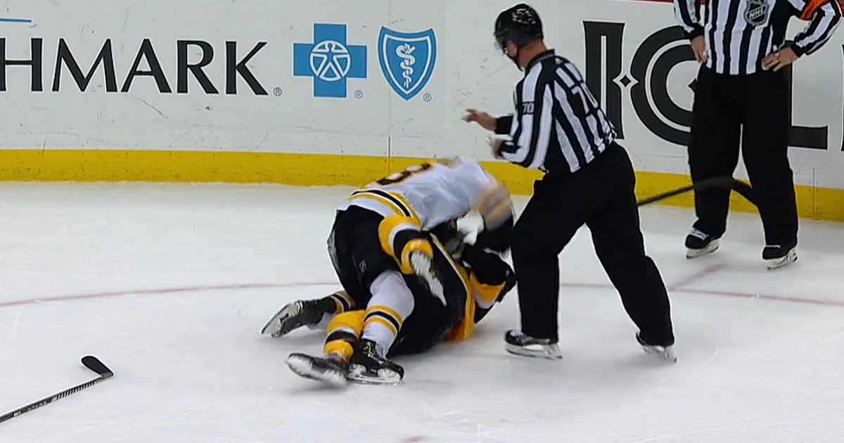 Brad Marchand and Kris Letang rough each other up behind the play.